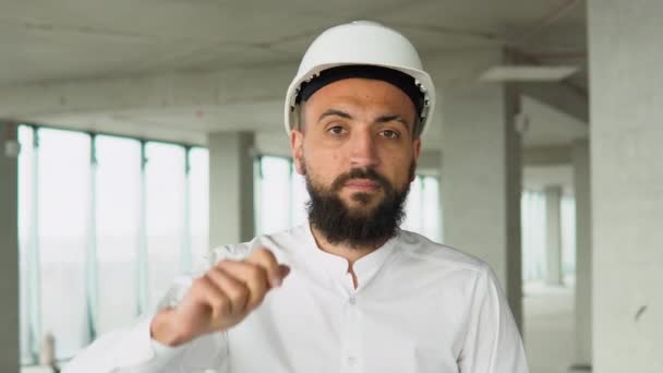 自信的阿拉伯土木工程师头戴安全帽 站在建筑工地上看着摄像机 — 图库视频影像