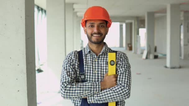 身着制服 头戴安全帽 看着摄像机的印度建筑工人站在办公中心建筑工地的画像 — 图库视频影像