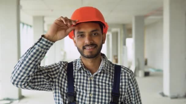站在建筑工地上 身穿制服 头戴安全帽 目不转睛地看着摄像机的自信的印度亚洲工人 — 图库视频影像
