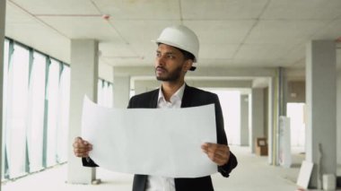 Hintli mühendis ya da mimar inşaat planı arıyor. İnşaat alanında beyaz kasklı.