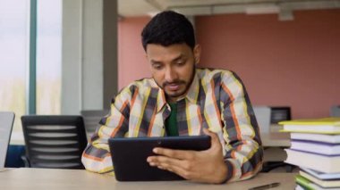 Tablet kullanan Hintli gülümseyen öğrenci, basit bir internet kursu, başvuruda online öğrenme, notlar yazma, sınava hazırlanma, eğitim videosu izleme