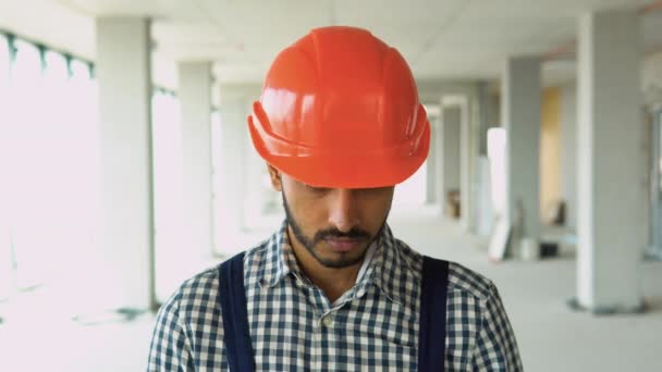 身着制服 头戴安全帽 看着摄像机的印度建筑工人站在建筑工地的画像 — 图库视频影像