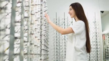 Kadınlar gözlüğü seçer. Bir sıra gözlük optikte. Gözlük dükkanı. Optik mağazasında gözlüklü dur. Görme düzeltmesi.