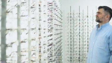 Optik Dükkanı 'nda. Üst düzey yaşlı erkek müşteri optik mağazada yeni gözlük seçip deniyor..