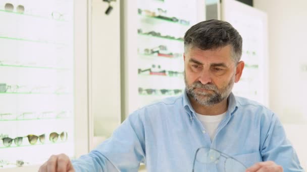 Vážné Starší Muž Výběru Brýle Rám Při Posezení Optickém Obchodě — Stock video