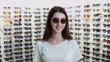 Optikte yeni güneş gözlüklü genç bir kadının portresi