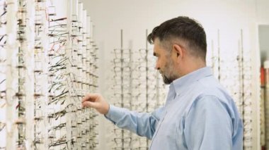 Optik Dükkanı 'nda. Üst düzey yaşlı erkek müşteri optik mağazada yeni gözlük seçip deniyor.