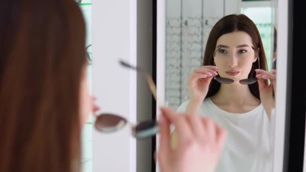 아름다운 선글라스를 선택하고 거울을 바라보는 — 비디오