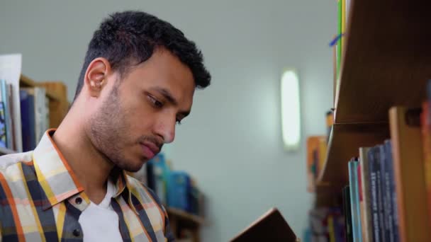 Universiteitsbibliotheek Talentvolle Indiase Jongen Staat Naast Boekenplank Leest Boek Voor — Stockvideo