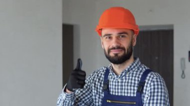 Miğferli olumlu insan müteahhidinin portresi. Apartmanda tamirat yapılıyor..