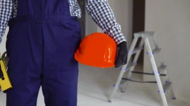 İnşaat işçisi. İnşaat alanında miğferi ve su pasları var. Bir apartman dairesinde ya da ofiste onarım.