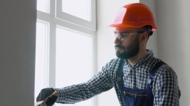 Tamirci duvarı fırçayla boyuyor.