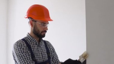 Tamirci duvarı fırçayla boyuyor.