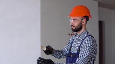 Tamirci duvarı fırçayla boyuyor.