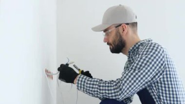 Elektrikçi elektrik ve televizyon prizlerine dekoratif çerçeve kuruyor.