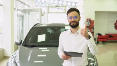 Otomobil Showroom 'daki İş Yeri' nde Yakışıklı Araba Satıcısı Pozisyonu 'nun Portresi, Yeni Otomobil Almaya Yardım Eden Ellerinde Panosu olan Genç Satış Merkezi Müdürü
