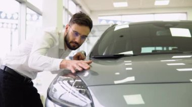 Mutlu Adam, yeni arabasının kapüşonlusunu kucaklıyor, Gülümseyen Milenyum Adamı, Oto Showroom 'da araba almayı hayal ediyor, Lüks Otomobil' in yüzeyine yaslanıyor.