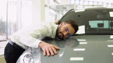 Mutlu Adam, yeni arabasının kapüşonlusunu kucaklıyor, Gülümseyen Milenyum Adamı, Oto Showroom 'da araba almayı hayal ediyor, Lüks Otomobil' in yüzeyine yaslanıyor,.