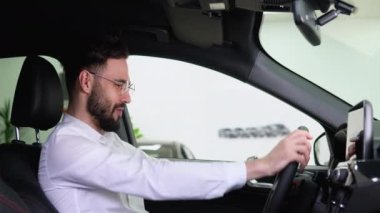 Mutlu adam atölyedeki yeni elektrikli arabasında oturuyor ve yeni araba alımını kutluyor. Araba al..