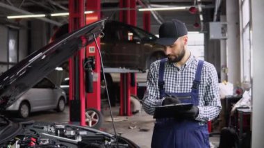 Genç tamirci araba servisinin durumunu kontrol ediyor..