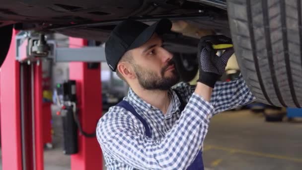 Profesjonalny Mechanik Nosi Rękawiczki Używa Grzechotki Pod Samochodem Portret Przystojnego — Wideo stockowe