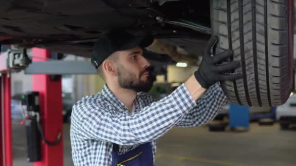 Doświadczony Mechanik Pracujący Pod Samochodem Warsztacie Samochodowym — Wideo stockowe