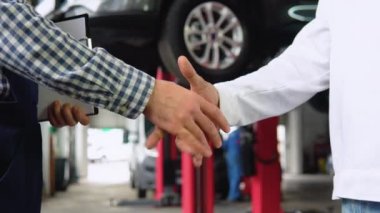 Gülümseyen oto tamircisi ve Hintli müşteri el sıkışıyor
