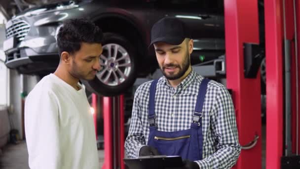 Mechanik Pokazuje Listę Kontrolną Samochodu Dla Klienta Zamazaną Asystentką Sprawdzającą — Wideo stockowe