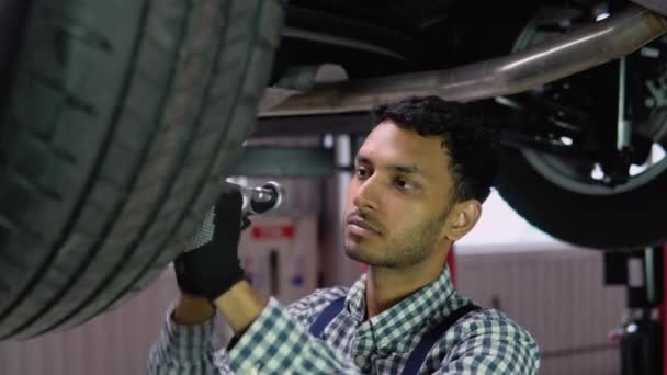 专业的印度修理工戴着手套 在车底下使用棘轮 现代清洁工场 — 图库视频影像