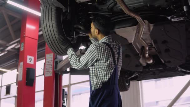 自動修理サービスで解除車の下で働くインドの自動車整備士の男 車サービス 修理メンテナンス — ストック動画