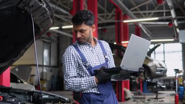 有经验的穿着制服的印度技师在修理汽车时正在使用笔记本电脑 — 图库视频影像