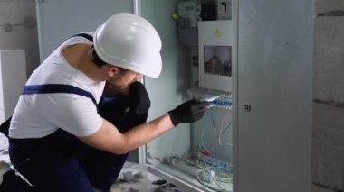 Yakışıklı sakallı elektrikçi elektrik kutusunu tamir ediyor ve koridorda tornavida kullanıyor..