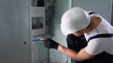 Yakışıklı sakallı elektrikçi elektrik kutusunu tamir ediyor ve koridorda tornavida kullanıyor..