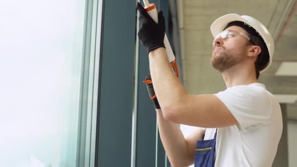Junger Arbeiter Versiegelt Fugen Von Bürofenster — Stockvideo