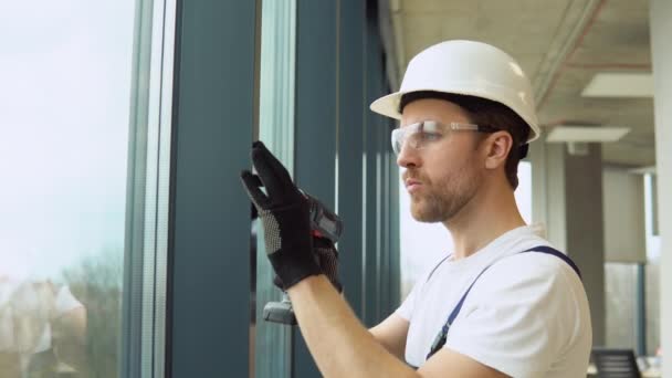 Seorang Tukang Reparasi Dalam Seragam Memperbaiki Jendela Pvc Kantor Baru — Stok Video