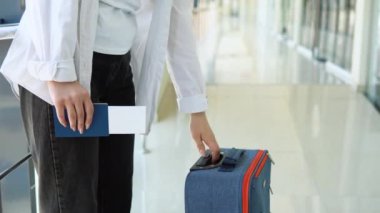 Elinde pasaport ve uçuş kartı olan bir kadın havaalanı koridorunda evrak kontrolü için bekliyor..