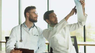 Tıbbi çok ırklı personel hastanede tartışıyor. Hintli ve Kafkas doktorlar laboratuvar testlerini tartışıyorlar