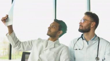Tıbbi çok ırklı personel hastanede tartışıyor. Hintli ve beyaz doktorlar röntgen sonuçlarını tartışıyorlar..