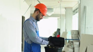 İnşaat işçisi inşaat alanında araç seçiyor. Ofiste onarım.