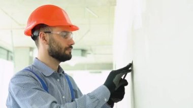 İnşaatçı sıva işçisi, inşaat alanının içindeki duvarı alçılıyor..