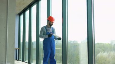 Üniformalı bir tamirci yeni ofise PVC pencereleri yerleştirir.