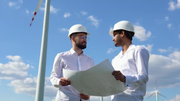 Dos Ingenieros Multiétnicos Discuten Plan Parque Eólico Frente Una Turbina — Vídeos de Stock