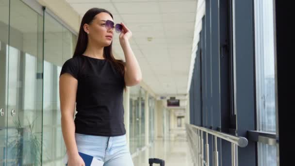 妇女戴上太阳镜 在机场走廊持护照和登机证 — 图库视频影像