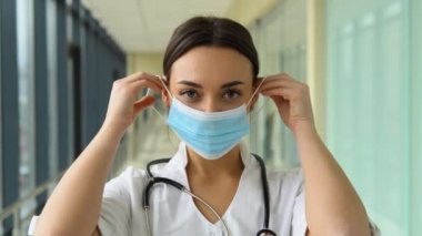 Kadın doktor koruyucu mavi bir maske takar..