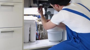 Teknisyen lavabonun altındaki su borusunu tamir etmek için İngiliz anahtarı kullanıyor. Bakım konsepti, su tesisatı sızıntılarını tamir etmek, mutfak lavabosunun giderini değiştirmek. Tıkanmış boruları temizlemek kirli ya da paslı.