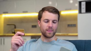 Akıllı telefondan online ödeme yapmak için kredi kartı kullanan bir adam. İnternetten alışveriş yapmak için cep telefonu kullanan beyaz bir adam. Adam uygulamadan kredi kartı işlemlerini kontrol etmek için akıllı telefon kullanıyor..