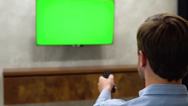 Młody Człowiek Siedzi Kanapie Ogląda Telewizję Poziomą Makietą Zielonego Ekranu — Wideo stockowe