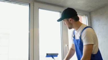 Ofisin penceresini temizleyen genç adam.