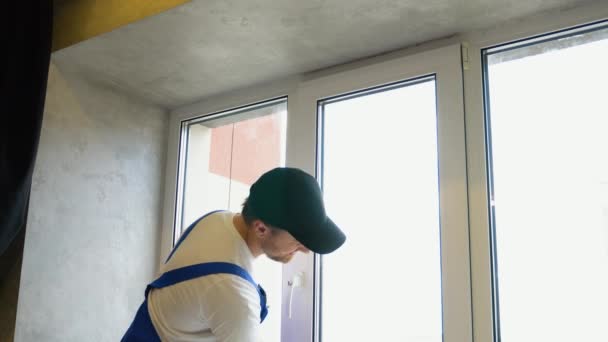 Hombre Joven Mono Azul Limpiando Ventana Apartamento — Vídeos de Stock