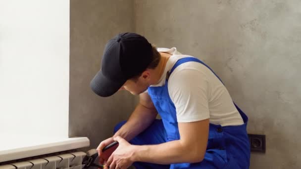 Junge Gut Aussehende Klempner Installieren Heizkörper Einem Leeren Raum Einer — Stockvideo